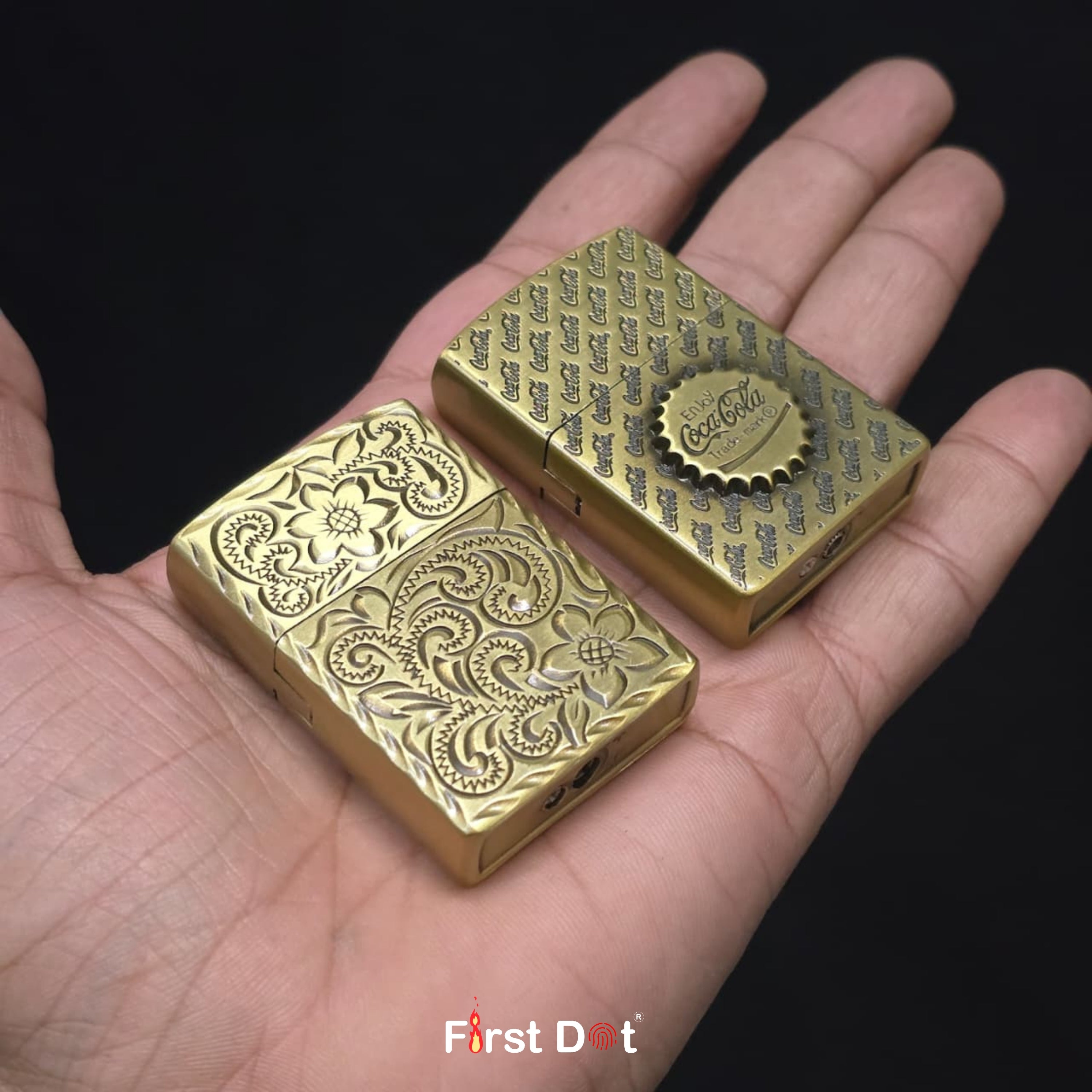 Two gold lighters with intricate designs held in a hand against a black background.