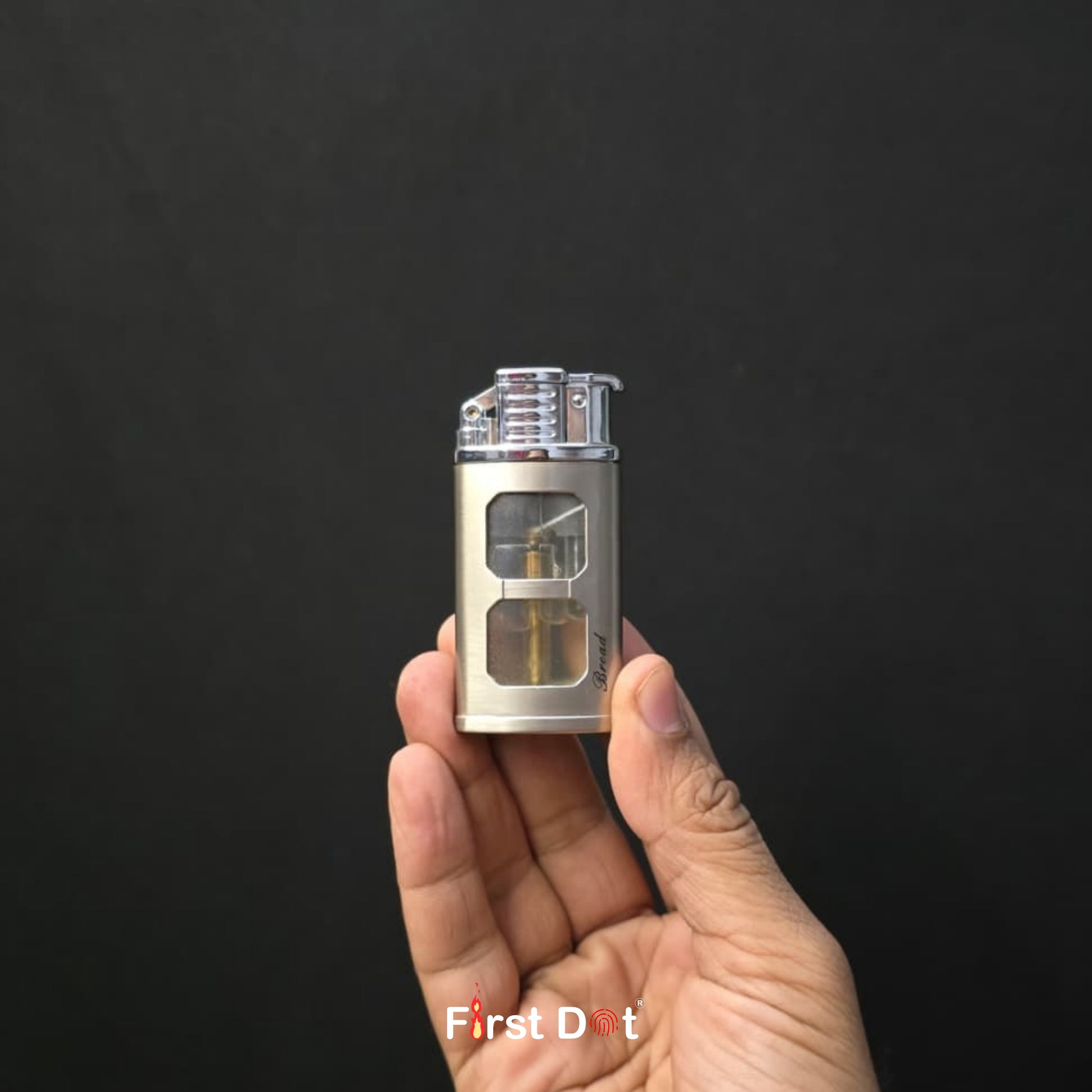 Hand holding a small metallic device against a black background with 'First Dot' branding.