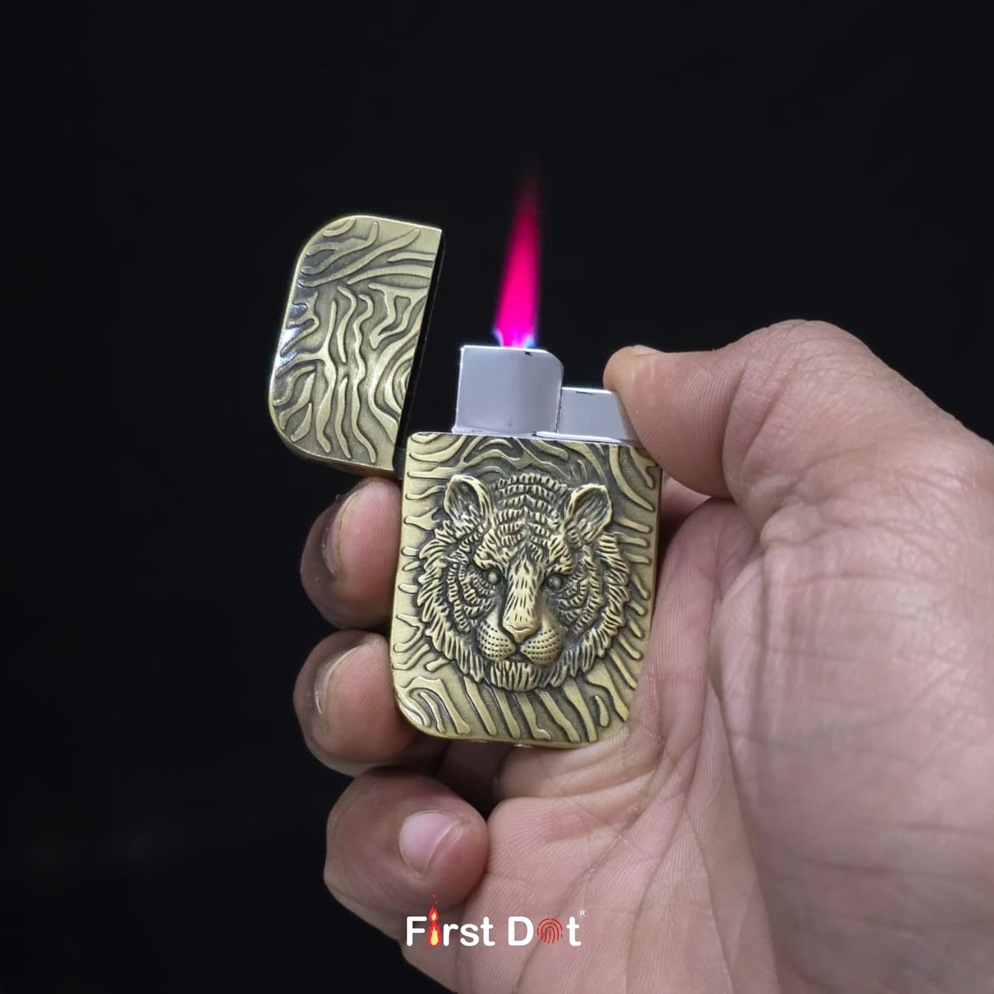Hand holding a brass lighter with tiger design, lit against a dark background.