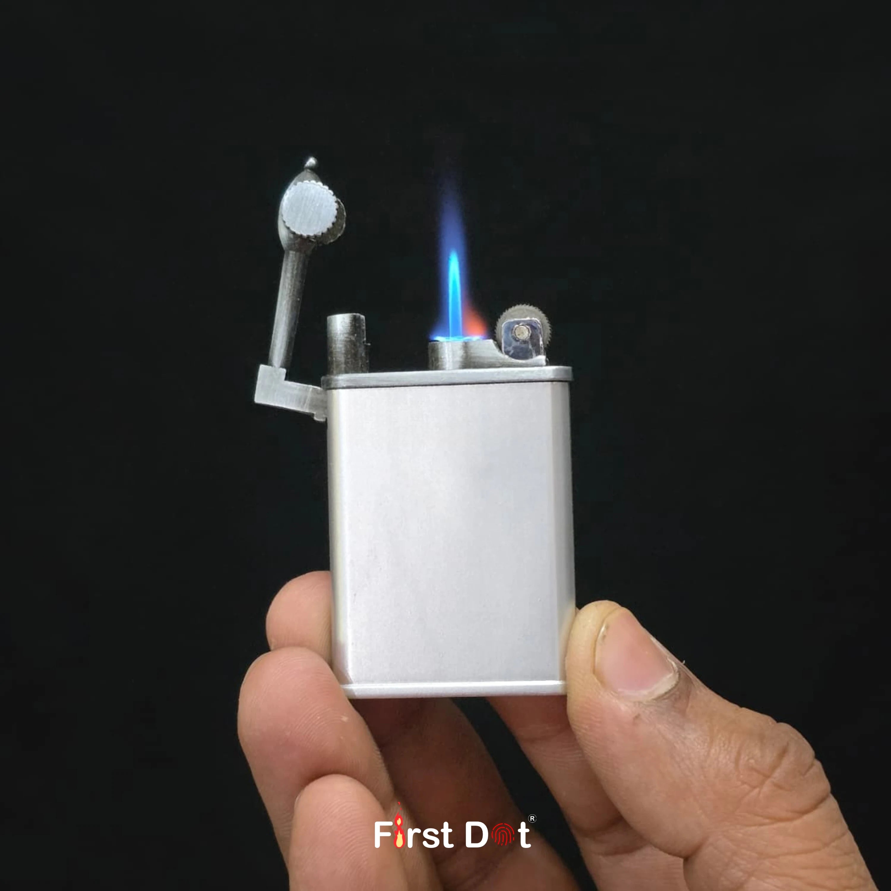 Hand holding a silver lighter with flame on a black background, featuring 'First Dot' branding.