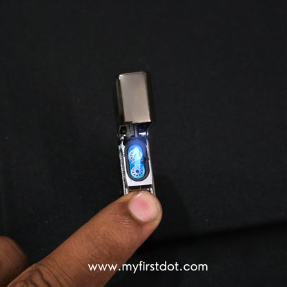 Small electronic device with a blue light on a dark background, held by a finger. Monarch Double Flame Torch Lighter Brushed Grey
